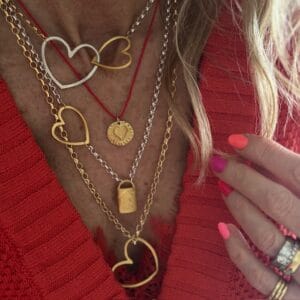 model wears layered heart necklaces in mixed metals